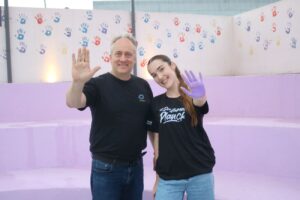 Diretor Umberto Malanga e ex-aluna Giovana Lorenzi em momento alegre no mural de mãos coloridas do Colégio Planck.