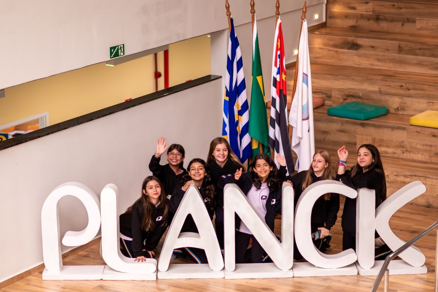 Estudantes atrás da placa Planck, a melhor escola de São José dos Campos.