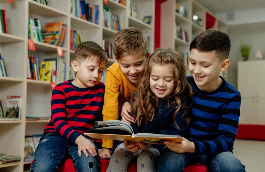 Você sabe como promover o interesse pela leitura em crianças do fundamental anos iniciais? A leitura é uma habilidade fundamental que contribui para o desenvolvimento cognitivo, social e emocional de uma criança, mas muitas vezes é desafiador fazê-las ter interesse em ler. Neste texto, conheça algumas estratégias eficazes para incentivar a leitura nos estudantes dessa faixa etária. Como promover o interesse pela leitura? Incentivar a leitura em idade precoce pode ajudar as crianças em seus processos de aprendizagem ao longo da vida, porque aprimora diversas competências e habilidades importantes na formação intelectual e emocional. Entre algumas vantagens da leitura, estão ajudar a desenvolver o vocabulário e também estimular a curiosidade das crianças por novos conhecimentos. Mas existe muitos outros benefícios de estimular o hábito da leitura entre as crianças, como: Traz desenvolvimento cognitivo apoiado; Aprimoramento das habilidades linguísticas; Traz boas estruturas de linguagem; Melhora habilidades de escrita; Estimula foco e concentração; Melhora habilidades de pensamento crítico; Estimula o uso da memória; Melhora imaginação e criatividade; Melhora habilidades de resolução de problemas; Fortalece as conexões cerebrais; Ajuda a aliviar o estresse; Amplia repertório de conhecimento na tenra idade; Prepara o estudante para o sucesso acadêmico; Assim, é mais que importante promover o interesse pela leitura entre as crianças desde cedo