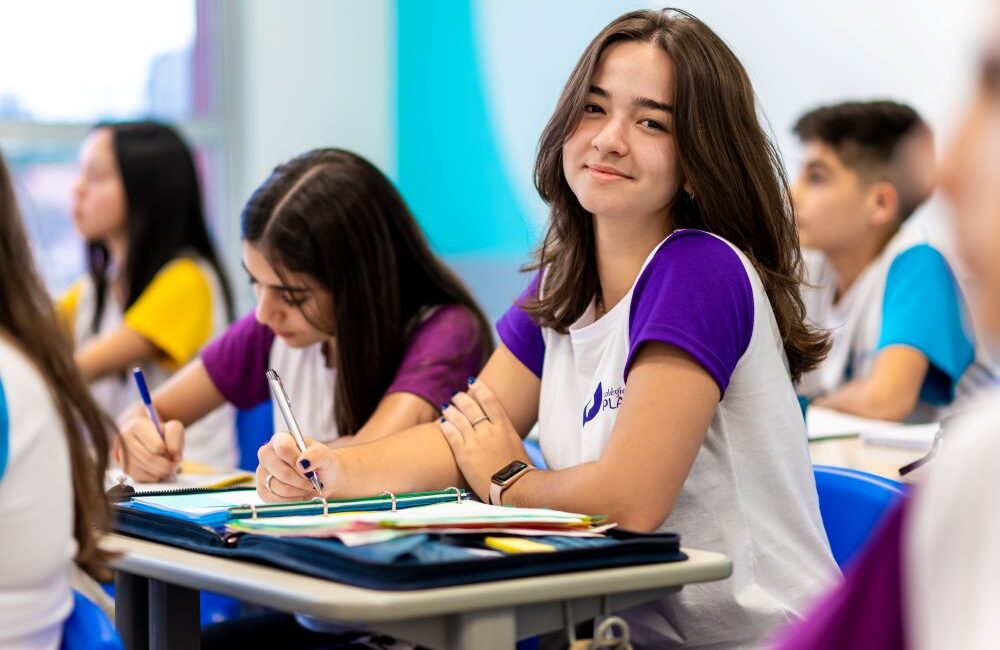 Estudante sentada em carteira estudando sobre como começar uma redação.