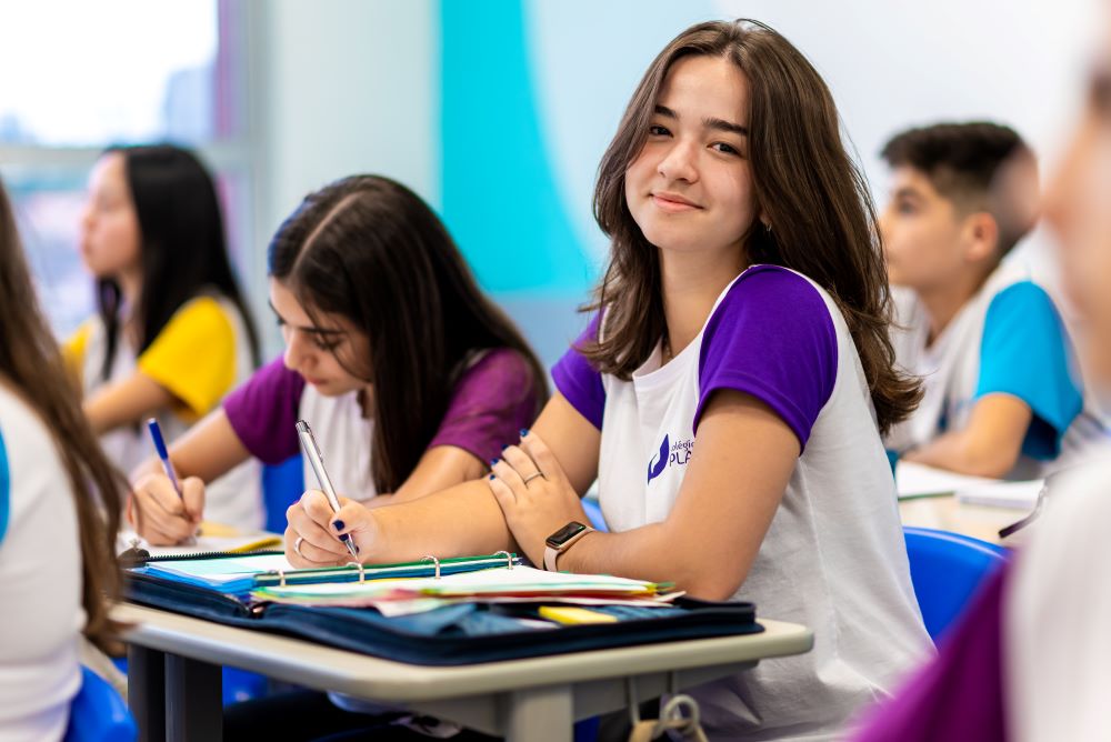 Estudante sentada em carteira estudando sobre como começar uma redação.