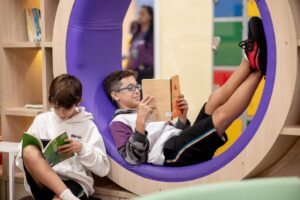 Estudante do 6º ano lendo livro em cabine circular.