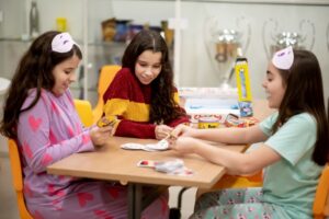 Estudantes do Colégio Planck sentadas à mesa brincando de jogo de cartas enquanto estão recuperados energias.