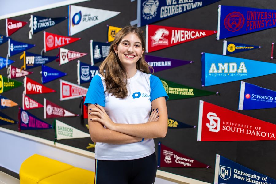 Estudante do Planck em frente a bandeiras de universidades estrangeiras.