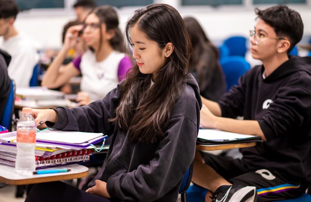 Estudantes do Colégio Planck sentados em carteira em sala de aula.