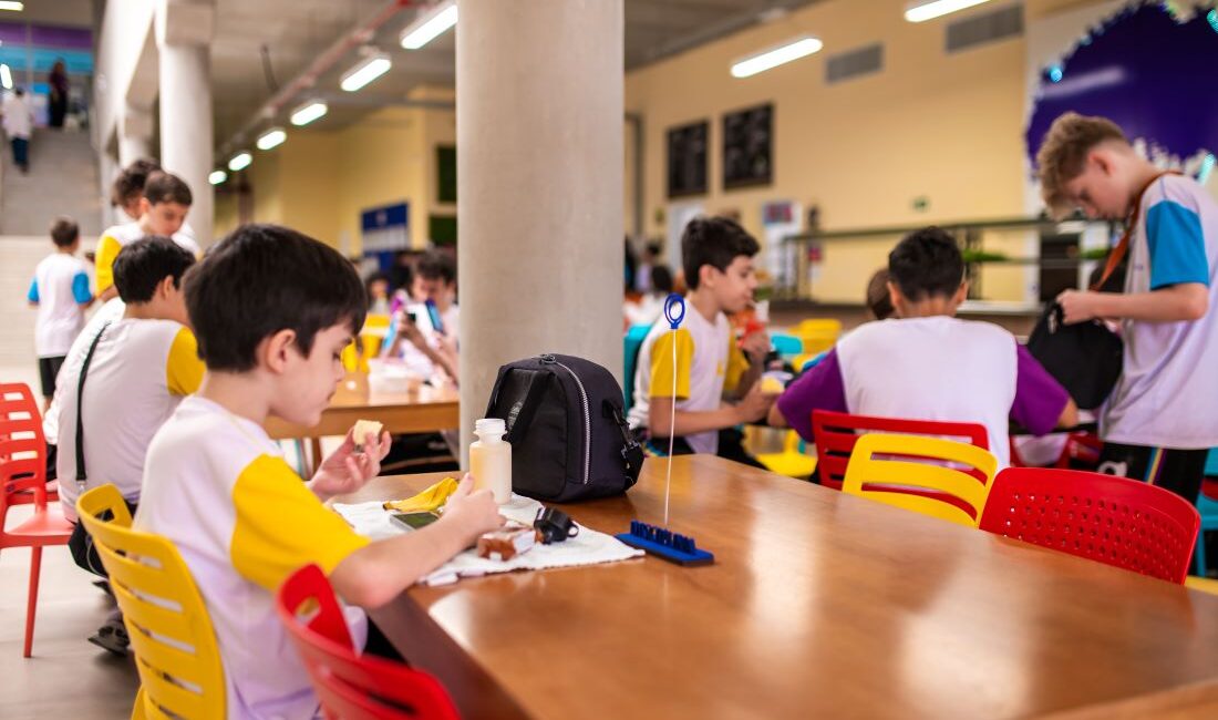 Estudantes se alimentando de lanches saudáveis em refeitório do Colégio Planck durante intervalo.