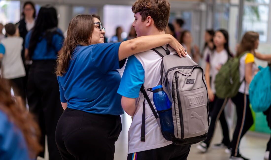 Profissional da equipe da escola mostrando acolhimento ao estudante com a volta das aulas