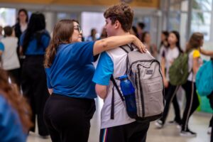 Profissional da equipe da escola mostrando acolhimento ao estudante com a volta das aulas