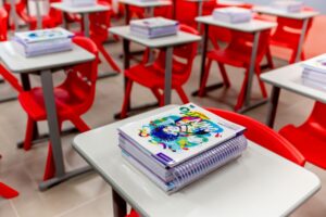 Cadernos e livros empilhados em carteira escolar, em uma sala de aula do Colégio Planck.