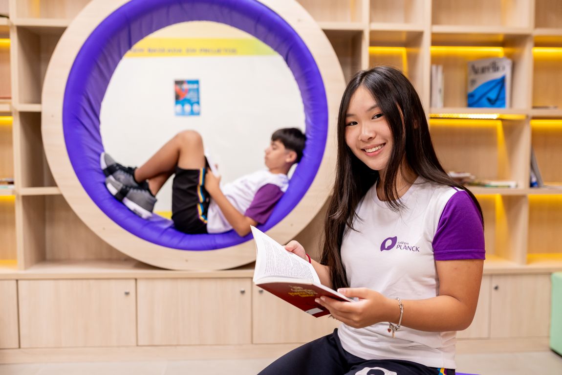 Estudante no ambiente do Colégio Planck com design moderno e pod de leitura: exemplo de espaço que estimula a educação exponencial.