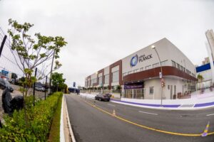 Fachada moderna do Colégio Planck com sinalização de boas-vindas destacando arquitetura acolhedora e acesso estruturado.