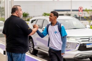 Professor recebendo estudante no portão da escola no retorno às aulas para demonstrar acolhimento no segundo semestre.