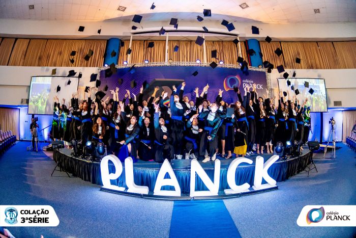 Estudantes do Colégio Planck comemoram aprovações em universidades lançando capelos no palco em evento oficial de formação.
