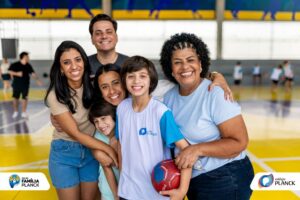 Grupo de adultos e crianças sorrindo e abraçados durante o Dia da Família do Colégio Planck, participando de atividades propostas pelo colégio familiar.