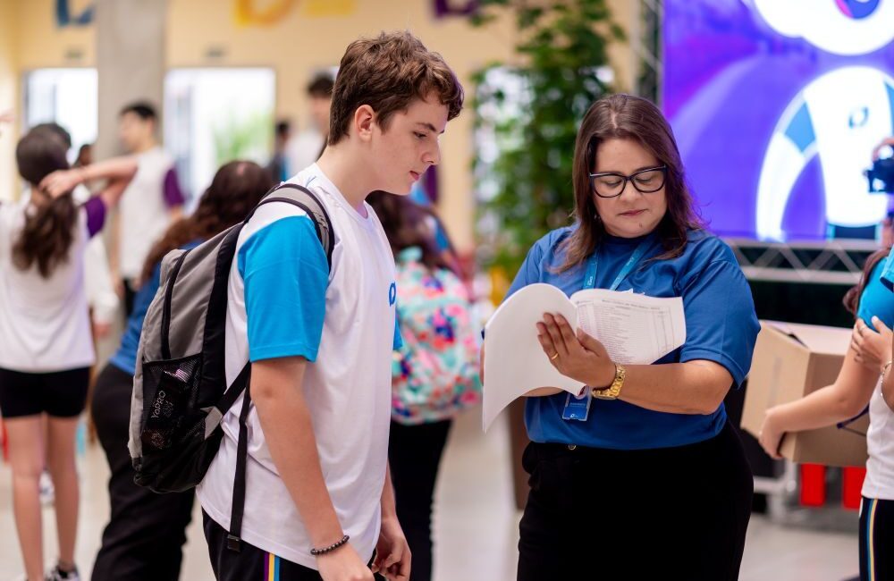 Estudante conversando com uma orientadora educacional, simbolizando momentos de feedback e orientação para o desenvolvimento de metas acadêmicas e socioemocionais.
