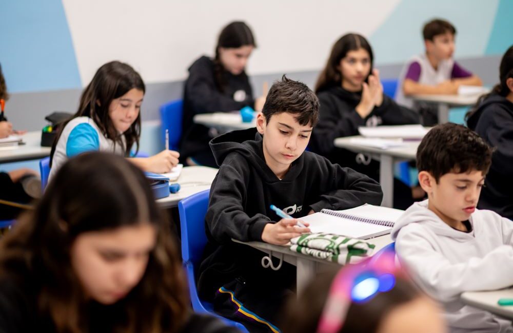 Estudantes do Colégio Planck concentrados em sala de aula, organizando cadernos e materiais durante a rotina estruturada de estudos no Ensino Fundamental II.