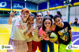 Grupo de estudantes do Colégio Planck sorrindo e interagindo em quadra esportiva durante evento de integração, demonstrando acolhimento e senso de pertencimento na transição para o Ensino Fundamental II.