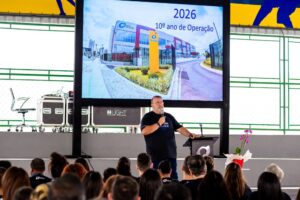 Apresentação escolar com público assistindo palestra sobre como escolher um colégio particular.