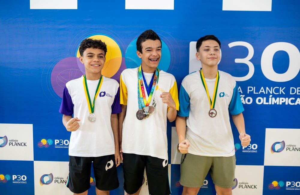 Estudantes com medalhas em evento escolar demonstrando o impacto das extracurriculares no desempenho acadêmico.