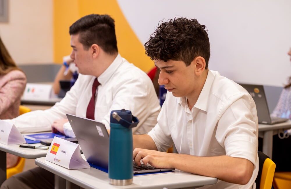 Estudantes do Colégio Planck participam de atividade acadêmica com notebooks em sala de aula, representando dedicação aos estudos e preparação para oportunidades internacionais como a Lester B. Pearson Scholarship.