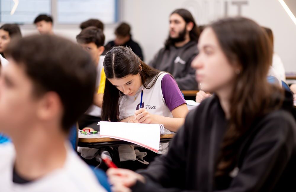 Estudante concentrada escreve em sala de aula, representando hábitos e disciplina que ajudam a sustentar resultados ao longo do Ensino Médio.