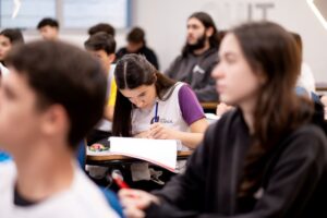 Estudante concentrada escreve em sala de aula, representando hábitos e disciplina que ajudam a sustentar resultados ao longo do Ensino Médio.