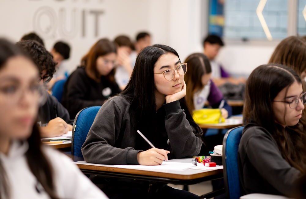 Estudantes concentrados durante prova em sala de aula, refletindo o que as universidades mais disputadas procuram além das notas.