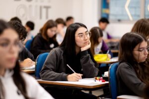 Estudantes concentrados durante prova em sala de aula, refletindo o que as universidades mais disputadas procuram além das notas.