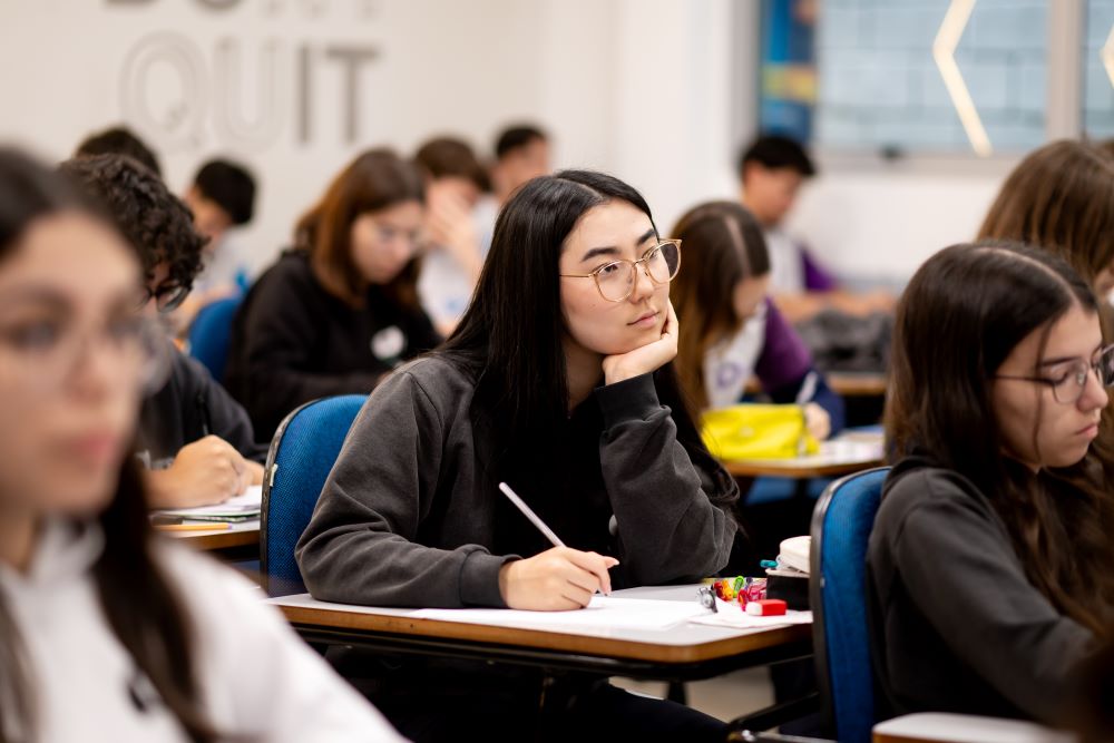 Estudantes concentrados durante prova em sala de aula, refletindo o que as universidades mais disputadas procuram além das notas.