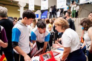 Estudantes do Colégio Planck conversando com representante de universidade em feira de profissões, buscando repertório para a escolha da carreira no Ensino Médio.