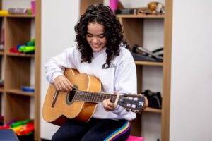 Adolescente do Colégio Planck toca violão durante atividade escolar, representando os benefícios de uma rotina equilibrada para o cérebro de adolescentes.